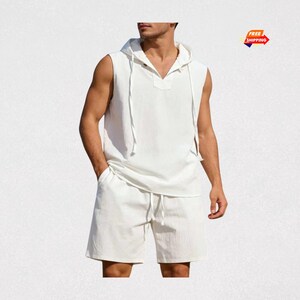 May include: A white sleeveless hooded shirt and matching shorts set. The shirt has a V-neck and drawstring, and the shorts have a drawstring waist. The set is made of a lightweight fabric.
