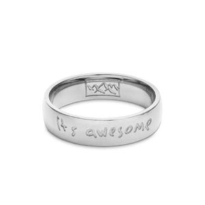 Op de afbeelding: Een zilveren ring met de gegraveerde tekst "It's awesome" aan de buitenkant. De ring heeft ook een bergketenontwerp aan de binnenkant.