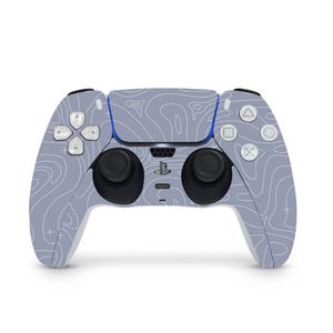 Könnte beinhalten: Ein grau-weißer PlayStation 5-Controller mit einem topografischen Kartenmuster. Der Controller hat schwarze Analogsticks, weiße Tasten und das PlayStation-Logo. Das Design bedeckt den gesamten Controller.