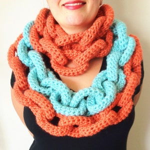 May include: A crocheted scarf in two shades of blue and orange. The scarf is made of thick yarn and has a chunky texture.