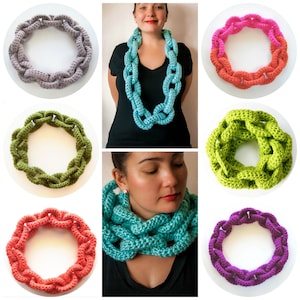 May include: A collection of crocheted chain link necklaces in various colours, including teal, green, purple, pink, and grey. The necklaces are made of thick yarn and have a chunky, textured look.