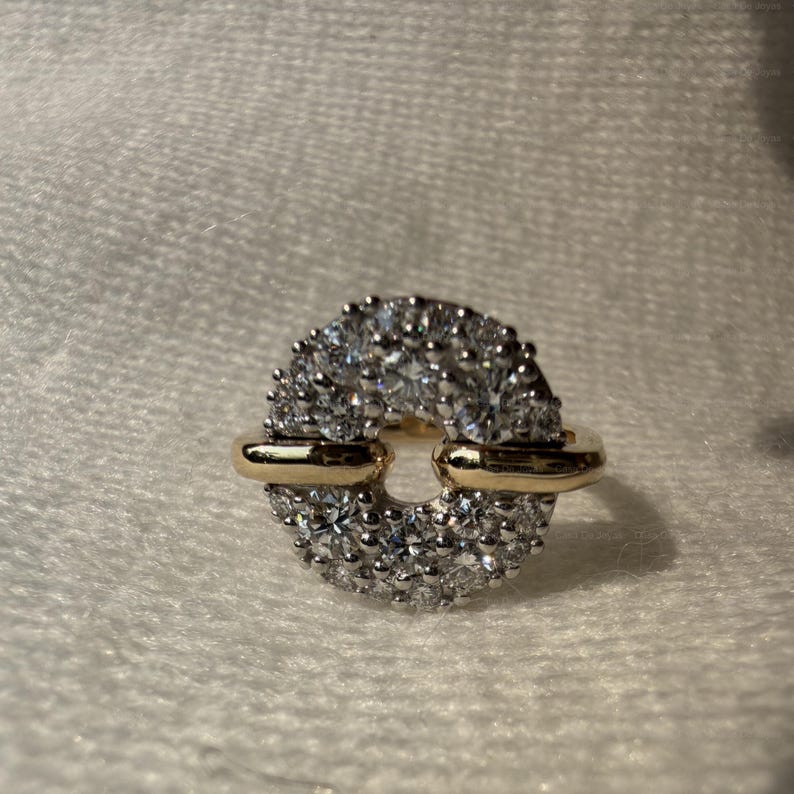 May include: A gold and silver ring with a circular design. The ring features a band of small, sparkling stones set in a silver metal, with gold accents on the sides. The ring is set against a white background.