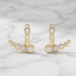 Puede incluir: Un par de pendientes ear jacket de oro que presentan un poste vertical con un diamante redondo de talla brillante y una sección curva inferior engastada con cinco diamantes redondos graduados en bisel, creando un diseño en capas.