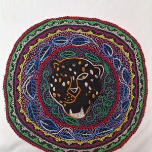 Könnte beinhalten: Eine weiße Keramik-Tasse mit schwarzem Henkel und dem Text "But First, Coffee" in fetter, schwarzer Schrift. Die Tasse steht vor einem verschwommenen Hintergrund, der eine gemütliche Umgebung suggeriert.