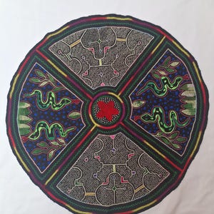 Könnte beinhalten: Runde Textilkunst mit schwarzem Hintergrund, mit vier Quadranten mit komplizierten Designs. Jeder Quadrant hat ein anderes Muster, darunter grüne Schlangen, Blätter und geometrische Formen. Die Mitte hat eine rote Blume. Der Rand ist mehrfarbig.