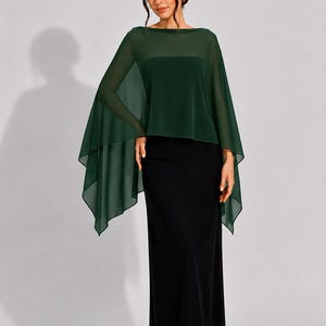 May include: A floor-length black dress featuring a straight-cut skirt and a strapless bodice, layered with a sheer, dark forest green chiffon capelet that drapes over the shoulders and arms with an asymmetrical, pointed hemline design.