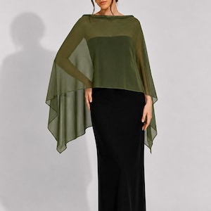 Puede incluir: Un vestido negro hasta el suelo con falda de corte recto y una capa transparente de color verde oliva. La capa tiene un escote barco ancho y cae holgadamente sobre los hombros y los brazos, creando una silueta fluida y superpuesta.