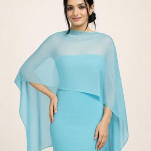 Peut inclure: Un châle en mousseline bleu clair transparent drapé sur les épaules, présentant une silhouette large et fluide avec un tissu doux et translucide qui descend le long des bras, associé à une robe sans manches bleu clair assortie.