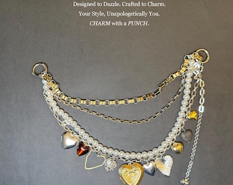 May include: A multi-strand bag charm with gold, silver, and pearl accents. The charm features heart-shaped pendants, a locket, and the text "A Little Charm. A Big Punch."
