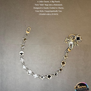 May include: Silver bag charm featuring star, clover, and diamond shapes. It has a lobster clasp and a key ring. The image includes text: "A Little Charm. A Big Punch. CHARM with a PUNCH."