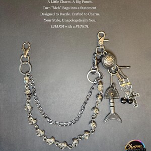May include: A silver-toned bag charm featuring a double chain with skull beads, a fish charm, a cross charm, and a decorative leather piece. The text on the image reads "A Little Charm. A Big Punch."