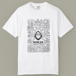 May include: White t-shirt with a black and white graphic. The design shows a ninja in a hood, set against a circuit board-style cityscape. The text "NINJA URBAN STRIKE" is displayed beneath the ninja illustration.