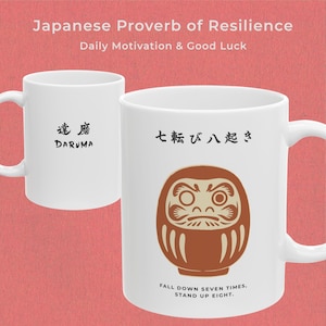 Peut inclure: Deux mugs en céramique blanche avec des textes et illustrations japonais noirs. L'un des mugs présente le mot "DARUMA", l'autre une illustration de poupée Daruma et la phrase "FALL DOWN SEVEN TIMES, STAND UP EIGHT." Le fond est rouge.
