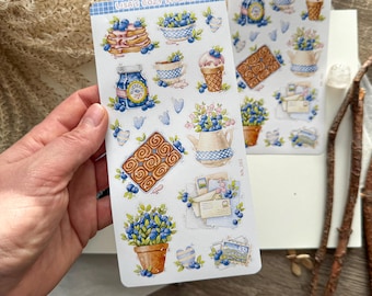 May include: Two sticker sheets featuring watercolor illustrations of blueberries, pancakes, ice cream cones, and cinnamon rolls. The stickers have a cozy, whimsical theme, with a blue and white color scheme.