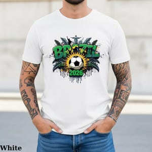 May include: A white ceramic mug with a black handle and the text "But First, Coffee" in a black, handwritten-style font. The mug is on a white surface.