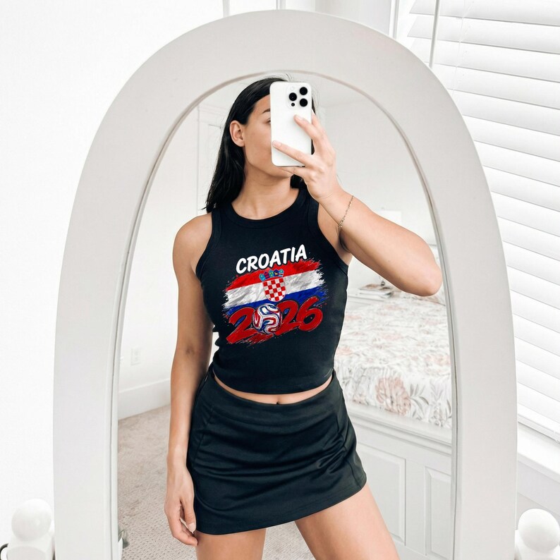 May include: A black sleeveless tank top featuring a graphic print of the Croatian flag, the word CROATIA, and the number 2026 with a football icon. The top is paired with a black athletic skirt, creating a coordinated two-piece outfit.