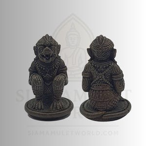 Peut inclure: Deux statues de bronze d'une figure anthropomorphe assise avec un visage de singe et des vêtements ornés. Les statues sont sur une base ronde. La statue de face a la bouche ouverte. L'adresse du site Web "SIAMAMULETWORLD.COM" est en bas.