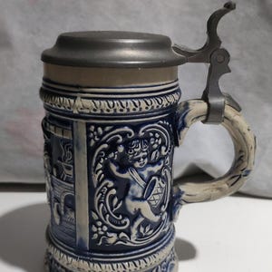 May include: A set of three ceramic mugs with a speckled, matte finish. The mugs are in cream, light grey, and dark grey. Each mug has a simple, minimalist design, ideal for coffee or tea.