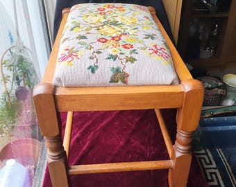 Taburete rectangular largo vintage con estampado floral bordado, patas de madera torneada y tapizado superior.