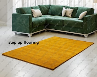 May include: A modern living room featuring a large, green sectional sofa with white pillows. A rectangular, golden-yellow rug is centered on the floor. The text "step up flooring" is visible on the floor.