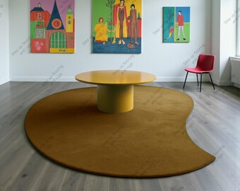 May include: A modern living room featuring a large, mustard-colored, semi-circular rug. A round, yellow table sits atop the rug. Three colorful paintings hang on the white wall. A red chair is positioned near a window.