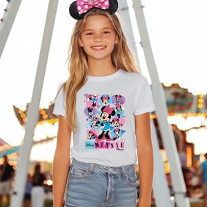 May include: A white t-shirt featuring a colorful graphic of Minnie Mouse in various poses, with the text "Disney Minnie Mouse". The shirt is worn with denim shorts and a black headband with a pink polka dot bow.
