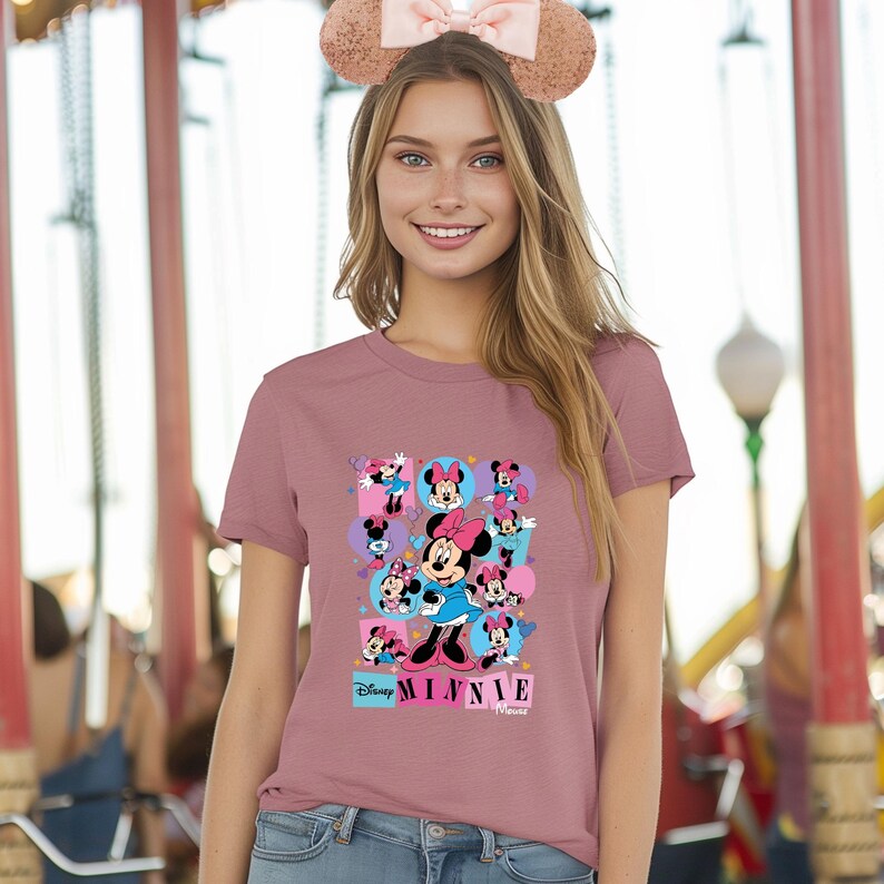 May include: Dusty rose t-shirt featuring a colorful graphic of Minnie Mouse in various poses. The design includes the text "Disney Minnie Mouse" in a playful font. The shirt is a classic crew neck style.