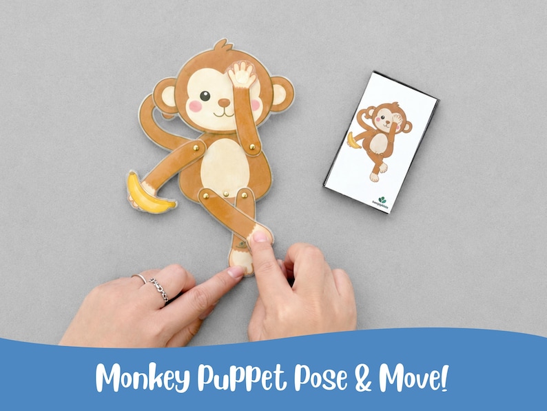 May include: A brown monkey puppet with a yellow banana, and a matching card. The puppet has movable limbs and is positioned with one hand over its eye. The card shows the same monkey pose. The text "Monkey Puppet Pose & Move!" is at the bottom.