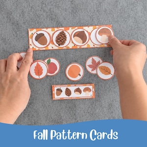 Puede incluir: Un conjunto de tarjetas rectangulares con patrones de otoño que presentan ilustraciones de bellotas, piñas, castañas, setas, calabazas y hojas. Las tarjetas incluyen recortes circulares para piezas de juego a juego con bordes naranjas.