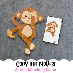 Può includere: Un giocattolo di scimmia in legno con arti mobili e una banana, accanto a una carta abbinata. La scimmia è marrone, beige e color crema. La carta presenta la stessa illustrazione della scimmia. Il testo "COPY THE MOVES! Action Matching Game" è in basso.