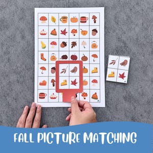 Può includere: Un gioco di abbinamento immagini a tema autunnale composto da un foglio a griglia rettangolare pieno di icone autunnali come funghi, foglie, zucche e tazze, insieme a una cornice rossa quadrata e un piccolo mazzo di quattro carte.