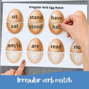 May include: Educational game featuring egg-shaped cards for learning irregular verbs. The cards are light brown with white bottoms and feature verb pairs like "sit/sat" and "stand/stood". The title "Irregular Verb Egg Match" is displayed.