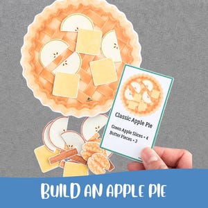 Op de afbeelding: Een papieren knutselset met een ronde taartbodem, vier appelschijfjes, drie stukjes boter, kaneelstokjes en walnoothelften. Een rechthoekige instructiekaart toont de tekst Classic Apple Pie, Green Apple Slices x 4, Butter Pieces x 3.
