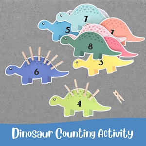 May include: A set of colorful dinosaur cutouts for a counting activity, featuring numbers 1 through 8 printed on each. Some dinosaurs have wooden clothespins attached to their backs. The text Dinosaur Counting Activity is printed at the bottom.