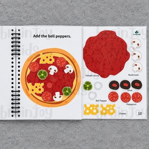 May include: A spiral-bound children's activity book open to a pizza-making page. The left page shows a pizza with toppings. The right page has tomato sauce, mushrooms, olives, bell peppers, pepperoni, and cheese. Text reads "Add the bell peppers."