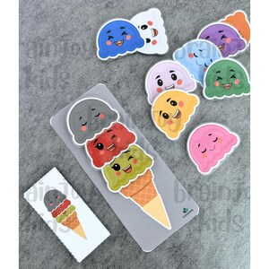 May include: A collection of colorful ice cream cone-shaped stickers and a matching ice cream cone puzzle. The stickers feature smiling faces in various colors, including blue, purple, green, and pink. The puzzle shows three scoops of ice cream.