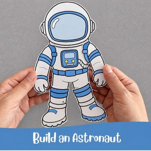 May include: A die-cut paper astronaut figure featuring a white suit with blue accents, a large helmet with a light blue visor, and a chest control panel. The figure is displayed against a grey background with the text Build an Astronaut below.
