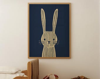 May include: A framed wall art print featuring a rabbit illustration. The artwork has a navy blue background with a cream-colored rabbit design. The rabbit is depicted with vertical stripes. The frame is made of light brown wood. The room also has a wooden bed and a toy basket.