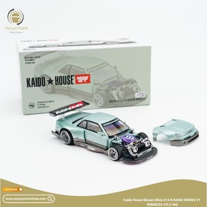 Op de afbeelding: Een 1:64 schaalmodel van de Kaido House Nissan Silvia S13-R Kaido Works V1 in metallic lichtgroen. De auto heeft een Advan-achtervleugel, een zichtbare paarse motorruimte en een afneembare motorkap. Het wordt getoond met de originele doos.