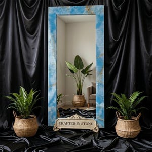 May include: A tall rectangular floor mirror with a polished blue onyx stone frame featuring natural veining. A decorative beige stone plaque at the base displays the text "CRAFTED IN STONE" in black lettering, accented by ornate carved scrollwork.