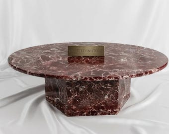 Mesa de centro de lujo Rosso Levanto redonda con tablero de mármol y pedestal hexagonal.