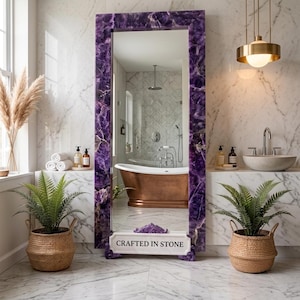 May include: A tall rectangular floor mirror featuring a thick frame made of deep purple amethyst stone. At the base of the mirror, a white rectangular plaque is prominently displayed with the black text "CRAFTED IN STONE" printed on its surface.