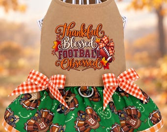 May include: A tan pet harness dress featuring the text Thankful Blessed FOOTBALL OBSESSED with a football graphic. The skirt is green with a pattern of turkeys wearing football helmets and jerseys, accented by orange and white gingham bows.