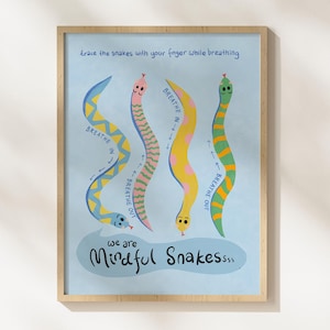 May include: A framed art print with four cartoon snakes in yellow, pink, green, and blue on a light blue background. Text includes "Breathe In" and "Breathe Out." The phrase "We are Mindful Snakes" is also present. The artwork is designed to encourage mindful breathing.