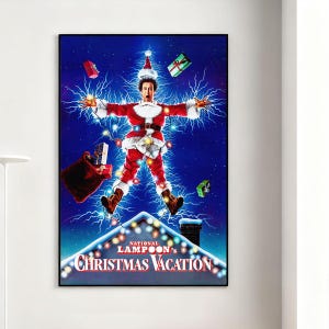 Op de afbeelding: Een ingelijste poster met een scène uit National Lampoon's Christmas Vacation. De afbeelding toont een man in een kerstmanpak, omringd door elektriciteit en kerstverlichting. De titel van de film staat onderaan de poster.