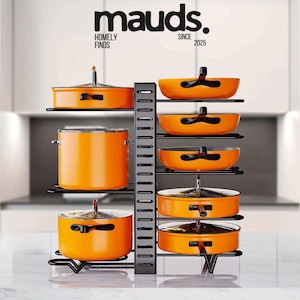May include: A black metal pot and pan organiser holding several orange pots and pans. The organiser has multiple shelves and a vertical support. The brand name "mauds" is displayed at the top of the image.