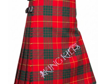 May include: A red kilt featuring a green and yellow plaid pattern with two black leather straps and buckles on the side. The text KING KILTS is printed in white on the front, accompanied by a small white lion logo near the bottom left corner.