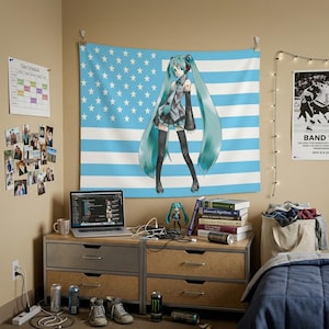 Puede incluir: Una habitación con una bandera con rayas azules y estrellas blancas, y un gráfico de un personaje con largo cabello turquesa. Una computadora portátil, libros y una pequeña figura están sobre una cómoda de madera. Zapatillas deportivas y latas de bebidas energéticas en el suelo.