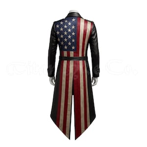 May include: A long black coat with an American flag design on the back and front. The coat features a black collar, sleeves, and belt. The flag design includes blue with white stars and red and white stripes.