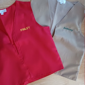 May include: Two red and beige vests with the names "Finley" and "Anthony" embroidered on them.